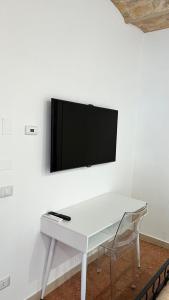 a white table with chairs and a tv on a wall at Boca Luxury Rooms in Tarquinia