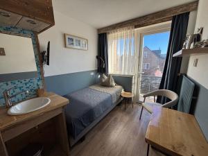 a bedroom with a bed and a sink and a window at Bed&Breakfast aan Strand in Katwijk aan Zee