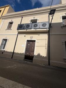 a white building with a brown door and a balcony at In centro da Carlotta in Olbia