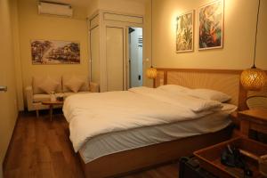 a bedroom with a large white bed and a chair at Silk Homestay LVC Central in Hanoi +4 photos