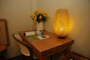 a table with a vase of flowers and a lamp at Silk Homestay LVC Central in Hanoi