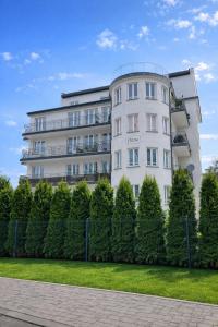 a white building with a fence in front of it at Penthouse Słoneczna Rapsodia - Nowoczesny Apartament z dużym Tarasem i Pięknym Widokiem przy Parku Zdrojowym in Rabka-Zdrój