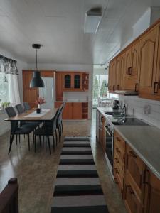 a kitchen with wooden cabinets and a table with chairs at Björktorpet och Soltorpet in Lepplax