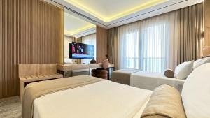 a hotel room with two beds and a flat screen tv at Solia Hotel in Mezitli