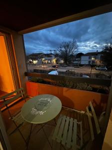 a table and chairs on a balcony with a view of a street at Appartement Soustons Les marronniers in Soustons