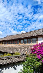 a building with a roof with purple flowers at In Spring Country Courtyard in Lijiang in Lijiang
