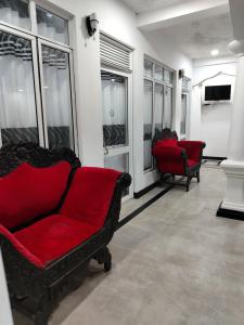 a living room with two red chairs and windows at Hotel Diamond Palace in Bibile
