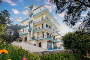 a white and blue building with balconies and trees at Kasauli Hills Hotel in Kasauli