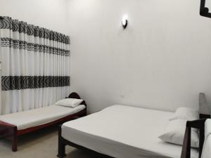 a white room with two beds and a curtain at Hotel Diamond Palace in Bibile +34 photos