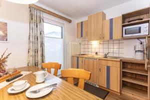 a kitchen and dining room with a wooden table and chairs at Neuhof Appartements in Maishofen