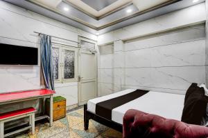 a bedroom with a bed and a tv and a couch at Hotel O ANANT ONE HOTEL AND BANQUETS in Ghaziabad