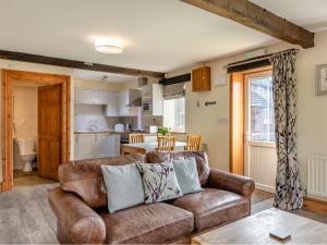 a living room with a brown couch and a kitchen at Milking Parlour - Uk48911 in Allonby