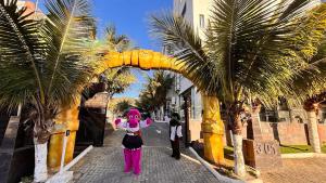 a person in a costume standing next to a palm tree at Hotel Recanto dos Dinossauros in Penha