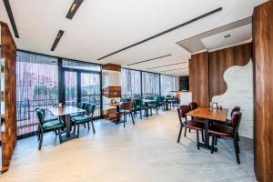 a restaurant with tables and chairs and large windows at Hilltown Airport Hotel & Restaurant in Taşoluk
