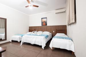 a room with two beds and a ceiling fan at Hotel Portela II - Av Principal e a 500m do Thermas dos Laranjais in Olímpia