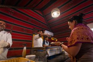 a woman is preparing food in a kitchen at Aladdin Camp in Disah