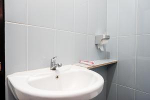 a white sink in a white tiled bathroom at RedDoorz Plus @ Kalpataru in Rampal +19 photos