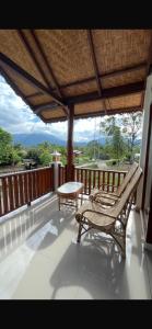 a porch with a chair and a table on a deck at Green Corner VILLA in Bukit Lawang