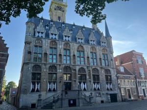 a large stone building with a clock tower at De Logeerkamer Gapinge in Gapinge