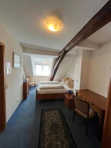a bedroom with a bed and a desk in a room at Hotel Iris- Pizzeria Ristorante La Taverna in Meersburg