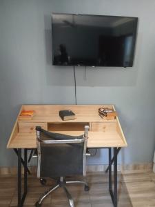 ein Schreibtisch mit Stuhl und ein Fernseher an der Wand in der Unterkunft Ibokwe homested in Hillandale