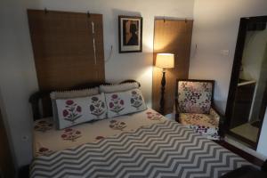 a bedroom with a bed and a chair and a lamp at The Turquoise Letterbox - Twin at Central in Kolkata