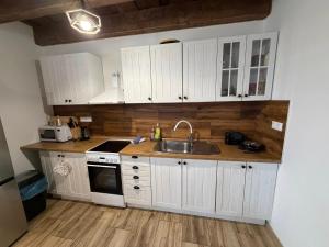 a kitchen with white cabinets and a sink at Wellness chata Rybárie in Klokočov