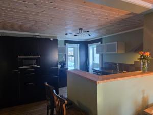 a kitchen with black cabinets and a counter with chairs at Fjellro appartment in Os +4 photos