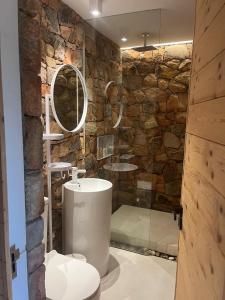 a bathroom with a stone wall with a toilet and a sink at Old Mac Daddy in Botrivier +8 photos