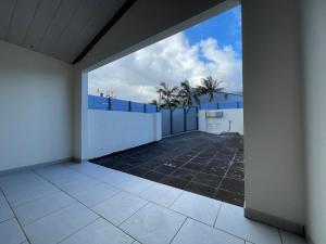 an empty room with a white fence and palm trees at Les volets de l'océan in Saint-Philippe