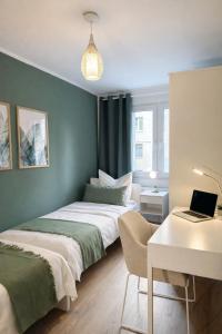 a bedroom with two beds and a desk with a laptop at Großzügiges Apartment am Limbecker Platz mit Cafés, Top Anbindung & Netflix in Essen