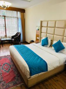a bedroom with a large bed with blue pillows at Hotel De Park in Shimla