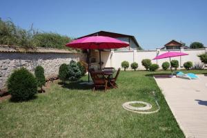 a patio with two chairs and a pink umbrella at Златна люспа in Bŭlgarevo