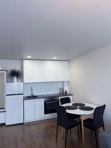 a kitchen with white cabinets and a table and chairs at EVA apartment in Marijampolė