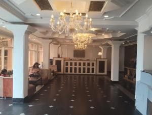 a lobby with a chandelier and a woman sitting on a couch at Hotel De Park in Shimla