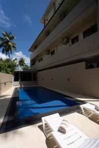 a swimming pool next to a building with two lounge chairs at Orchid Resort By Paradise in Habaraduwa Central