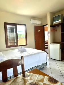 a bedroom with a white bed and a window at Pousada garopaba in Garopaba