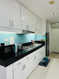 a kitchen with white cabinets and a black counter top at Poolside Condo in Subic Bay in Olongapo