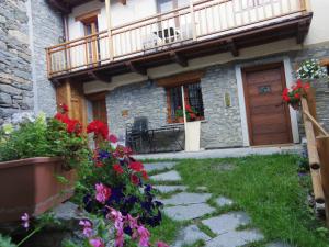 une maison avec un balcon et des fleurs devant elle dans l'établissement Lo Ni di Candolle, à Gignod