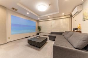 a living room with a couch and a large screen at Kawasaki Central House in Kawasaki