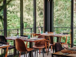 a restaurant with tables and chairs and large windows at HEJMO Hostel in Hossegor