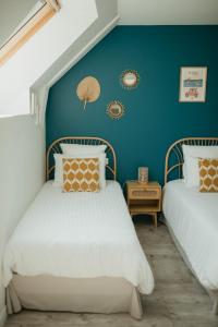 two beds in a room with a blue wall at Parenthèse in Le Vivier-sur-Mer