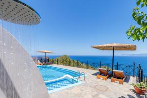 a swimming pool with two chairs and umbrellas at Villa Sea Horizon in Skopelos Town
