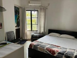 a bedroom with a bed and a desk and a window at Chaithritha Ladies Homestay in Trivandrum