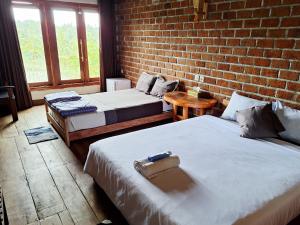 two beds in a room with a brick wall at Bunga Maliq Bungalow Lombok in Tetebatu