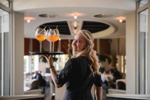a woman holding up a tray with three wine glasses at Kasteeltje Hattem in Roermond