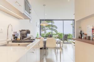 a kitchen with a sink and a table with chairs at Quinta Golfinho in Arco da Calheta