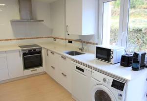 a white kitchen with a sink and a microwave at Villa Emilio Foz in Foz