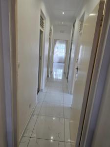 a hallway with white walls and a white tile floor at Tranquility Guest House in Bulawayo