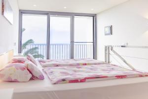 a white bedroom with two beds and a window at Quinta Golfinho in Arco da Calheta +33 photos